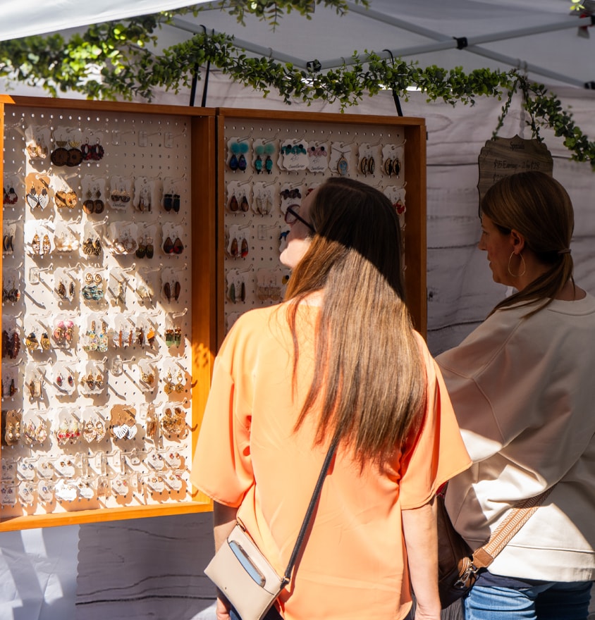 Shoppers browsing handmade earrings at an arts vendor booth