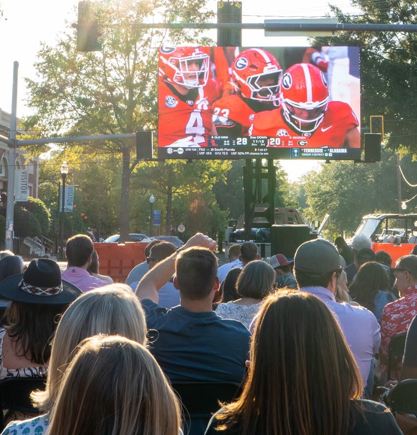 Crowd watching football game on outdoor screen at Deep Roots Festival EndZone