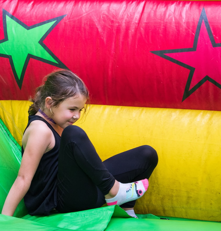 Girl sitting at the bottom of a colorful inflatable slide