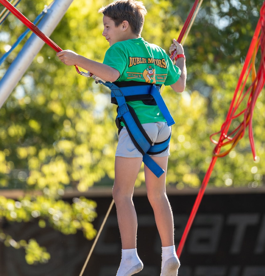 Child on bungee trampoline harness at outdoor festival